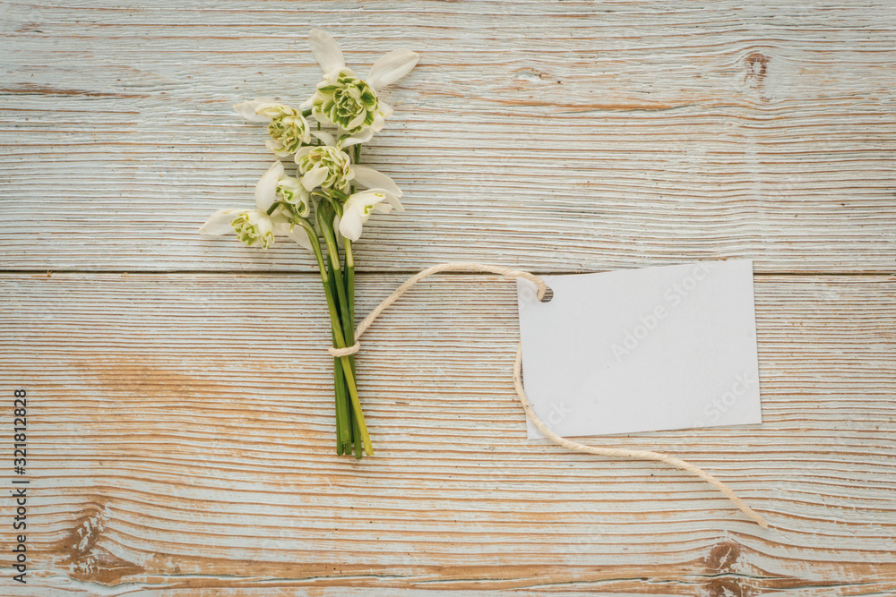 Posy of white flowers on white wood backgroun with blank label Posy of white flowers on white wood backgroun with blank label
