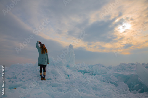 girl in blue wnter jacket staying at ice hummock in frozen lake Kapchagai near Almaty, Kazakhstan
