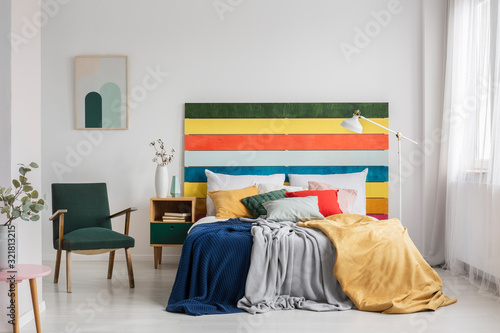 Retro armchair in modern bedroom interior with rainbow colored headboard © Photographee.eu