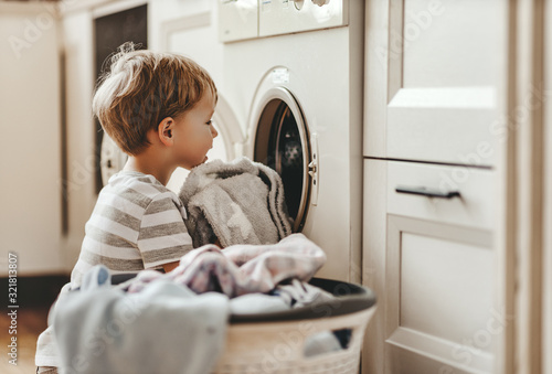 Canvas Print happy  householder child boy in laundry   with washing machine.