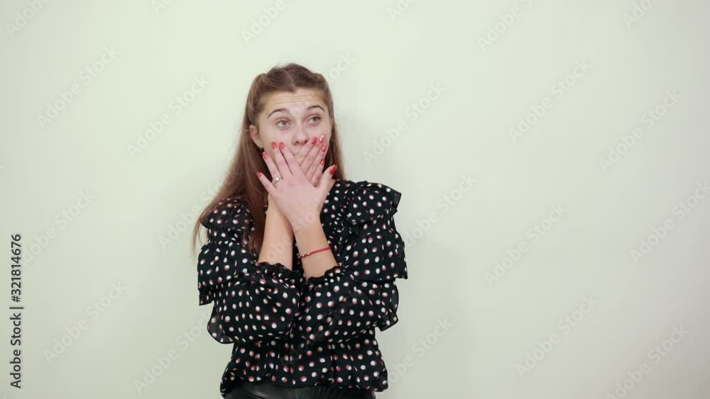 Fair-haired beautiful girl in a black dress with white circles woman shocked by surprise, covered mouth with hands Fair-haired beautiful girl in a black dress with white circles woman shocked by surprise, covered mouth with hands