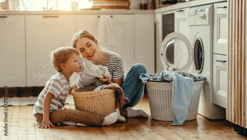 Happy family mother housewife and child   in laundry with washing machine .