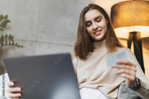 Girl paying for online purchases on internet. Great shopping opportunities from world retailers for international customers. Young woman performing online payment with bank card with bonuses photo