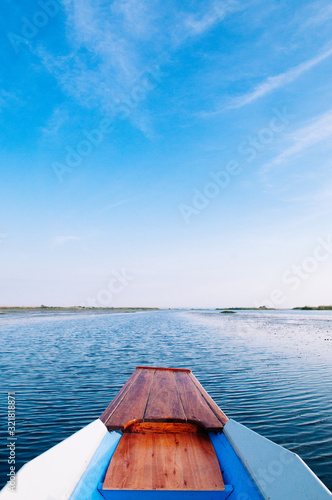 Thai wooden boat bow travel in peaceful blue Nong Harn lake - Udonthani, Thailand. Famous red lotus lake in winter © PixHound