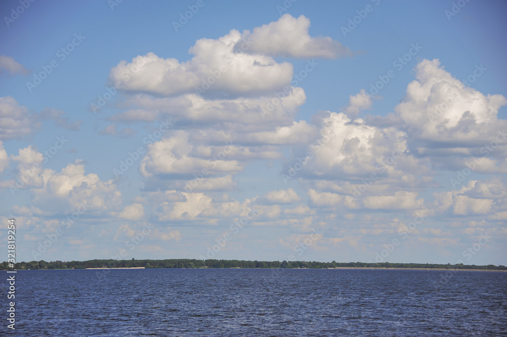 Fluffy cumulus clouds over a pond in the summer. sunny day