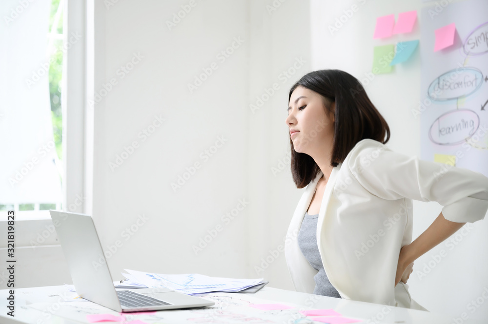 Office syndrome concept. Young asian business woman feeling pain have a backache after working on computer laptop for a long time Office syndrome concept. Young asian business woman feeling pain have a backache after working on computer laptop for a long time