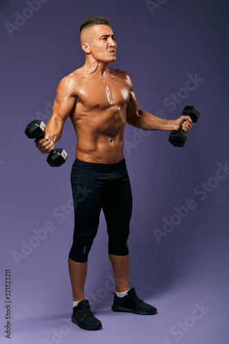 agressive tired sweaty man is keen on bodybuilding  full length side view photo. isolated blue background  studio shot