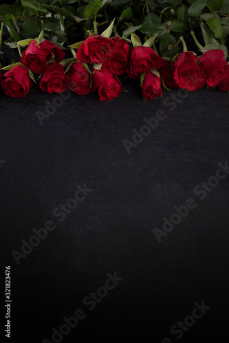 Valentine Day frame. Red roses on the upper edge on a dark background with a copyspace