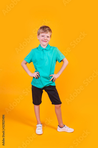 Full length portrait of cute little boy in stylish clothes looking at camera and smiling