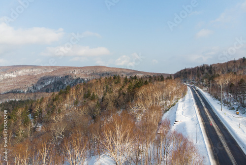 Oblique view of a road between Otaru and Niseko during early winter morning with sunlight making the hill side golden