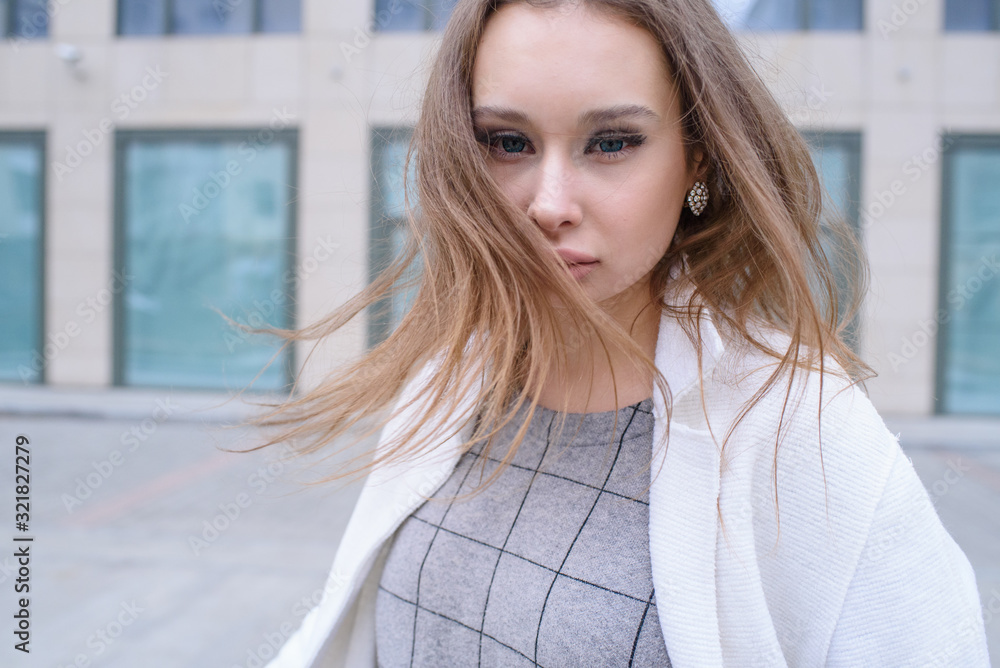 Young beautiful girl walking in a white coat in cloudy weather. Portrait photo session. Fashion. Young beautiful girl walking in a white coat in cloudy weather. Portrait photo session. Fashion.