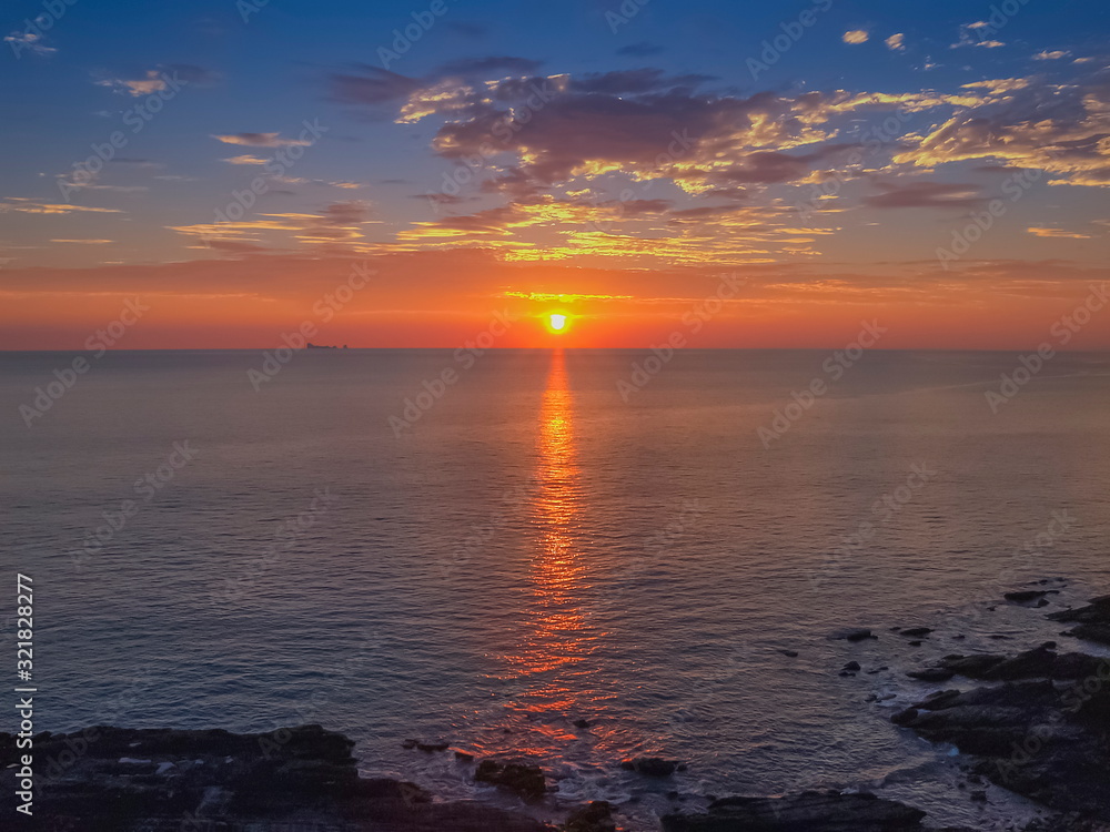 Obraz premium view seaside evening of many clouds moving above the sea with red sun light and cloudy sky background sunset at Tanod Cape (Laem Tanod), Mu Ko Lanta National Park, Lanta island, Krabi, south Thailand.