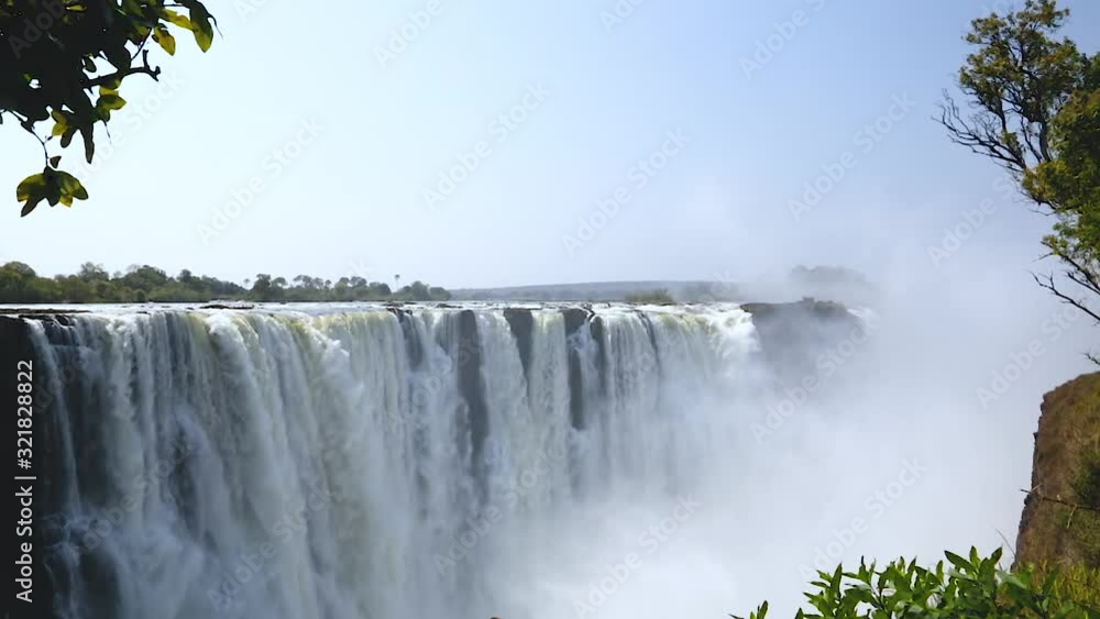 Slow left to right panning motion of water cascading over the cliffs in full force on the Zimbabwe side of Victoria Falls on a sunny day in Zimbabwe, Africa Slow left to right panning motion of water cascading over the cliffs in full force on the Zimbabwe side of Victoria Falls on a sunny day in Zimbabwe, Africa