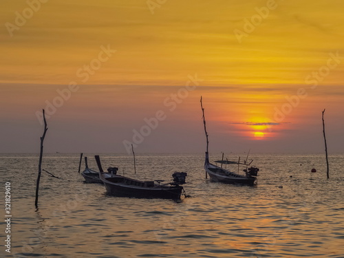 view seaside evening of fishing boats floating in the sea with orange sun light in the sky background, sunset at Klong Hin Beach, Ko Lanta island, Krabi, southern of Thailand.