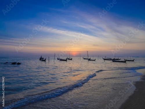 view seaside evening of fishing boats floating in the sea with orange sun light and blue sky background  sunset at Klong Hin Beach  Ko Lanta island  Krabi  southern of Thailand.