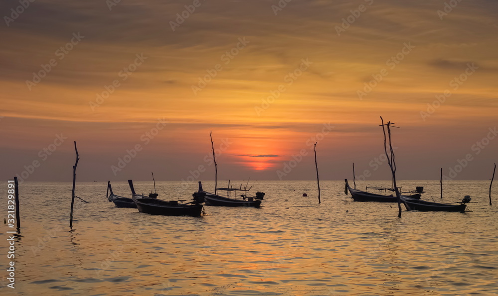 view seaside evening of fishing boats floating in the sea with orange sun light in the sky background, sunset at Klong Hin Beach, Ko Lanta island, Krabi, southern of Thailand.