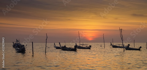 view seaside evening of fishing boats floating in the sea with orange sun light in the sky background, sunset at Klong Hin Beach, Ko Lanta island, Krabi, southern of Thailand.