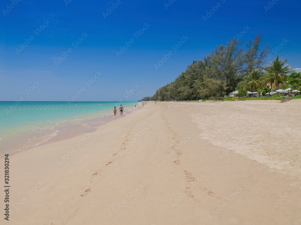 view of white sand beach with tourists walking and blue-green sea with blue sky background, Phra Ae Beach, Ko Lanta island, Mu Ko Lanta National Park, Krabi, southern of Thailand.