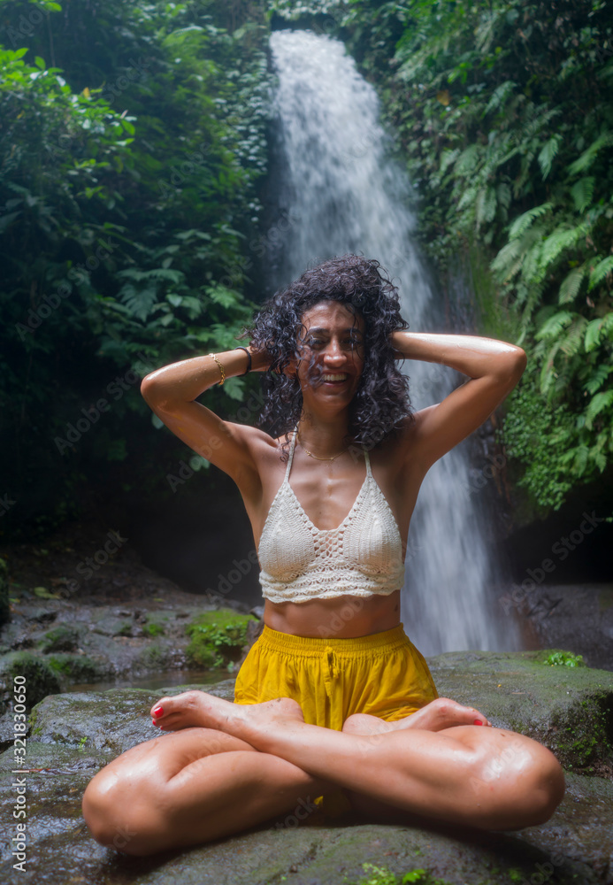 outdoors tropical lifestyle portrait of young attractive and happy hipster girl enjoying nature excited feeling free at amazing beautiful waterfall in exotic holidays travel