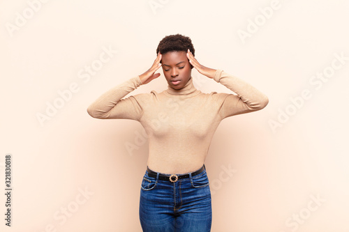 young pretty black womanlooking concentrated, thoughtful and inspired, brainstorming and imagining with hands on forehead photo