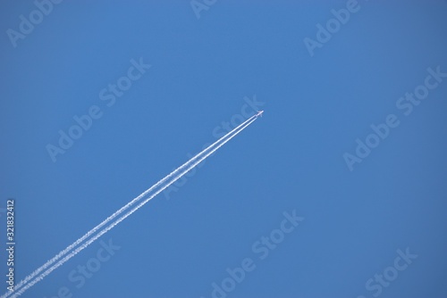 Aircraft flying through the sky blue, Condensing traces in the background.