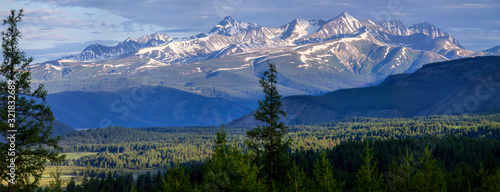 Forest and snow-capped mountain peaks, morning view. Panorama landscape.