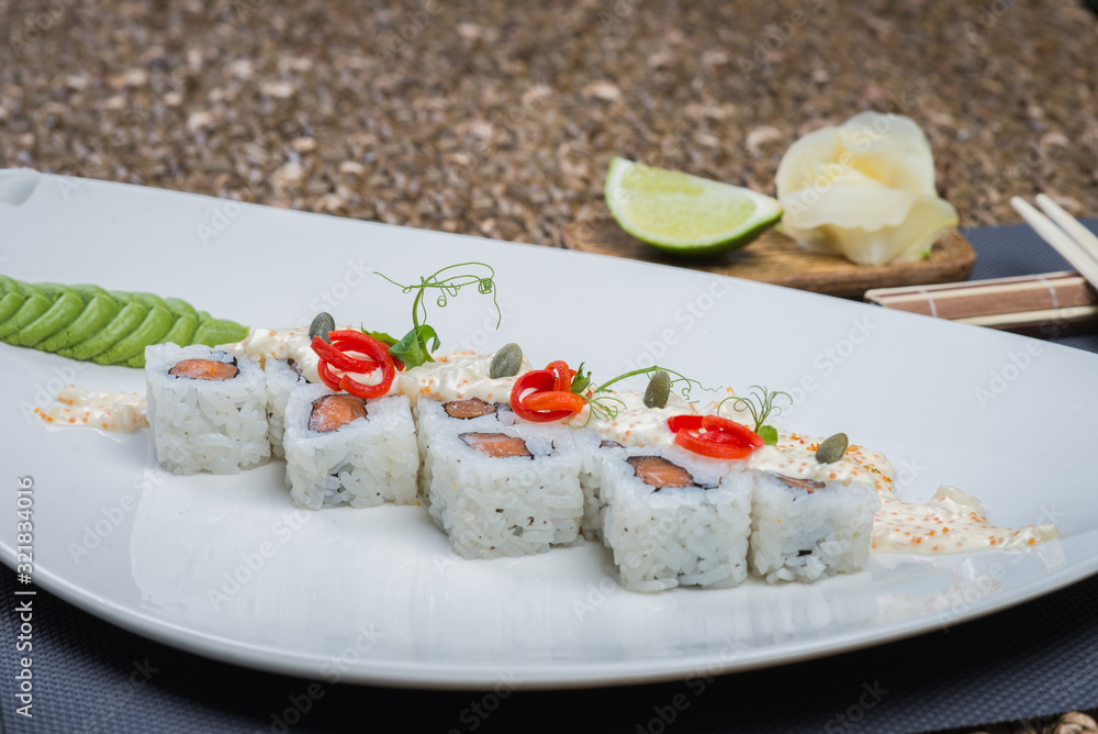 Traditional rolls with fish and rice on a white plate with sauce and wasabi. Japanese food. Traditional rolls with fish and rice on a white plate with sauce and wasabi. Japanese food.