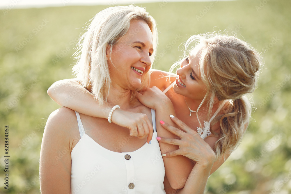 Adult mother with daughter. Beautiful girl in a white dress. Family in a summer field Adult mother with daughter. Beautiful girl in a white dress. Family in a summer field