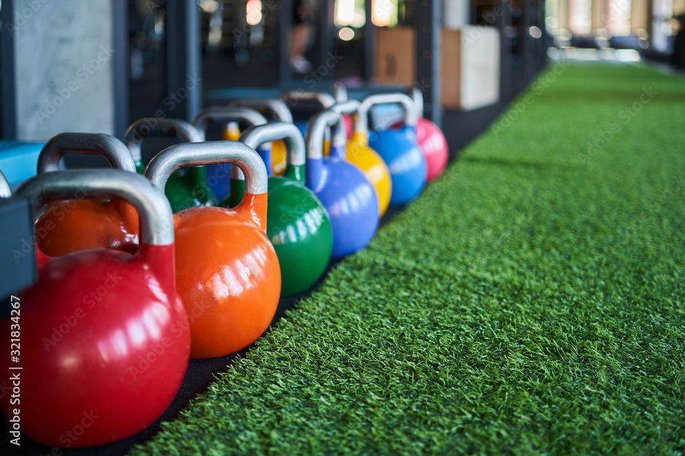 Colorful kettle bells in row on floor.