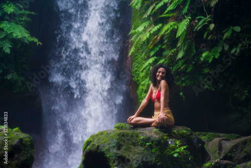 outdoors lifestyle portrait of young attractive and happy hipster woman enjoying nature feeling free at amazing beautiful waterfall in exotic holidays travel destination