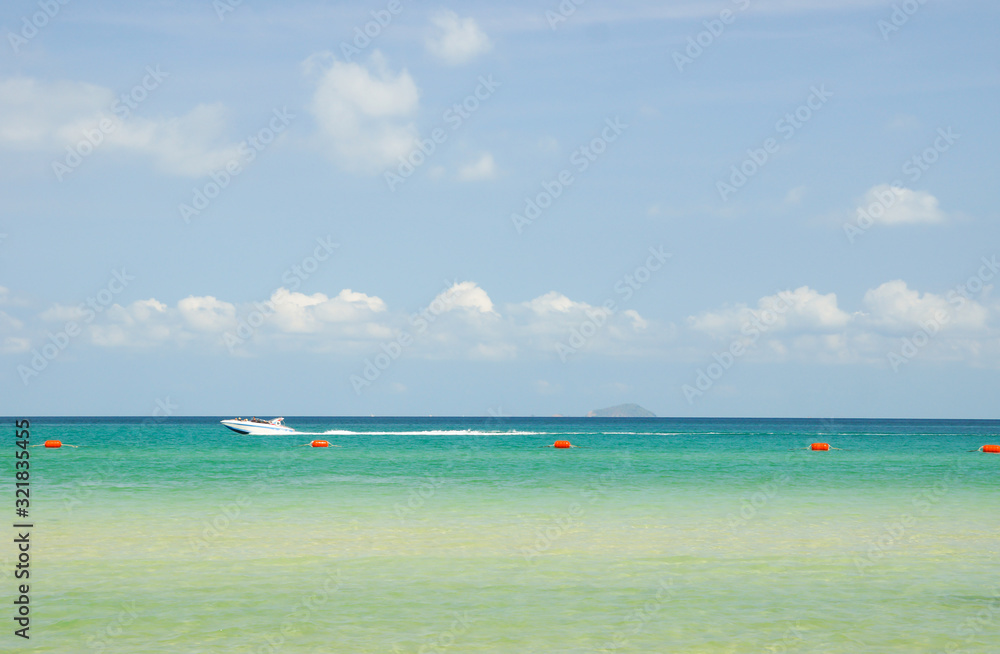 Speedboat sailing along the beach on a sunny day.