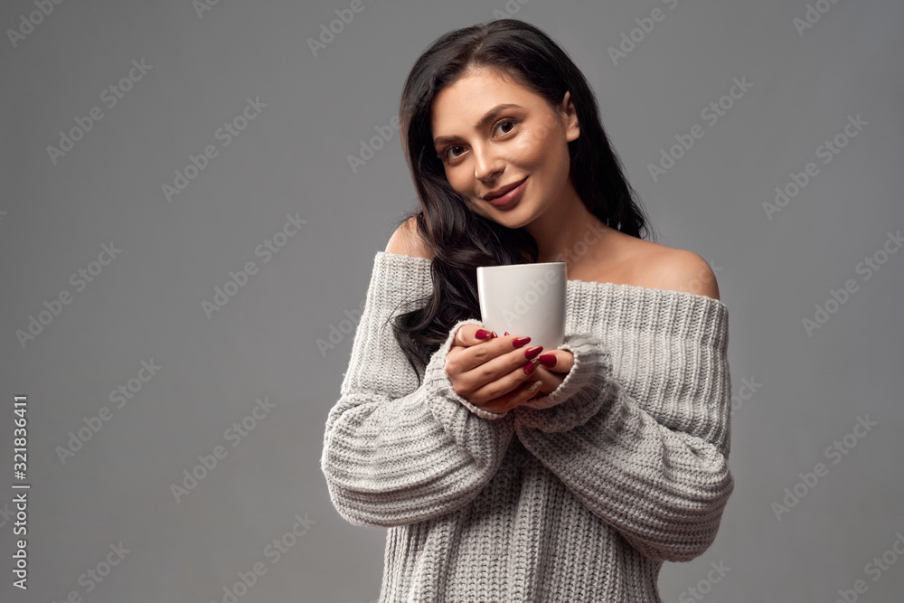 Brunette model warming hands with cup.
