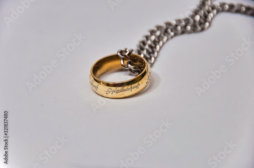 Golden ring with chrome chain on white surface. photo