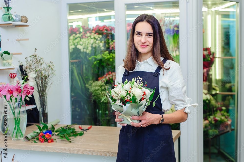 The owner of a flower shop makes a bouquet with white roses