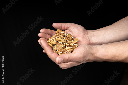 Peeled walnut kernels in male hands on a black background