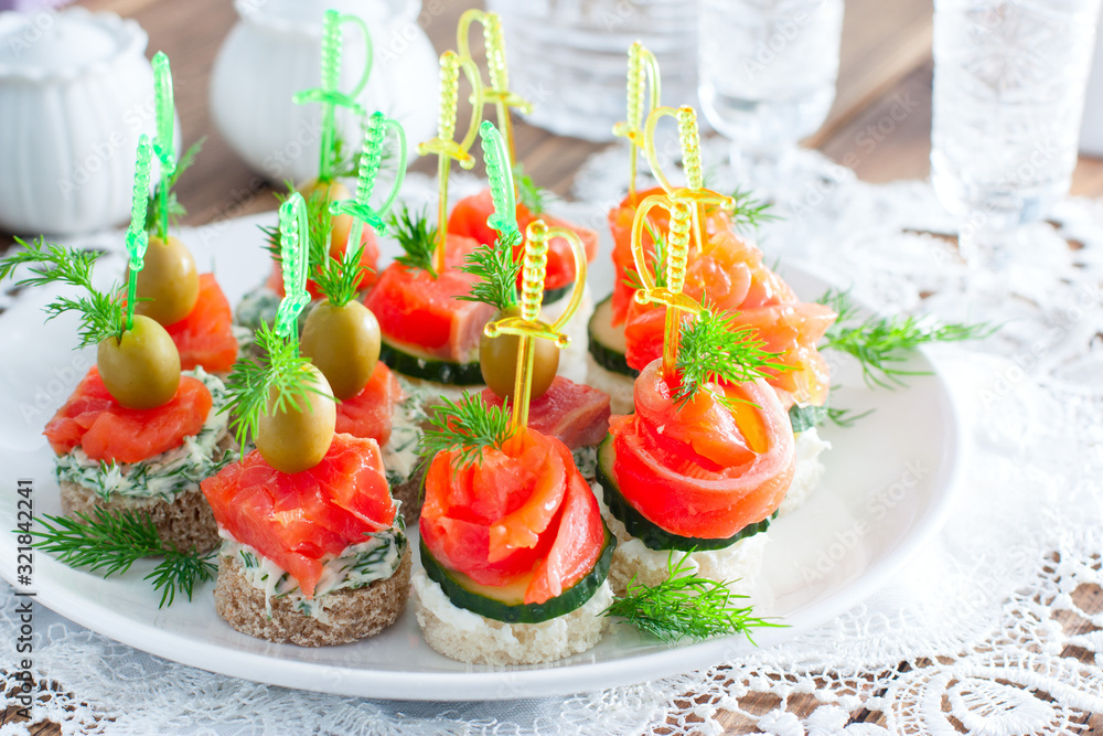 assorted canapes with salmon on white and black bread on a white plate, selective focus assorted canapes with salmon on white and black bread on a white plate, selective focus
