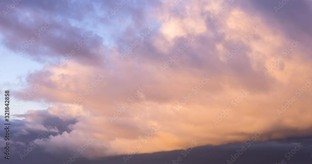Large cumulus cloud glowing orange and red in sunset time. Close-up of changing cloud formation and coloring from orange to scarlet and dark grey at the end Large cumulus cloud glowing orange and red in sunset time. Close-up of changing cloud formation and coloring from orange to scarlet and dark grey at the end