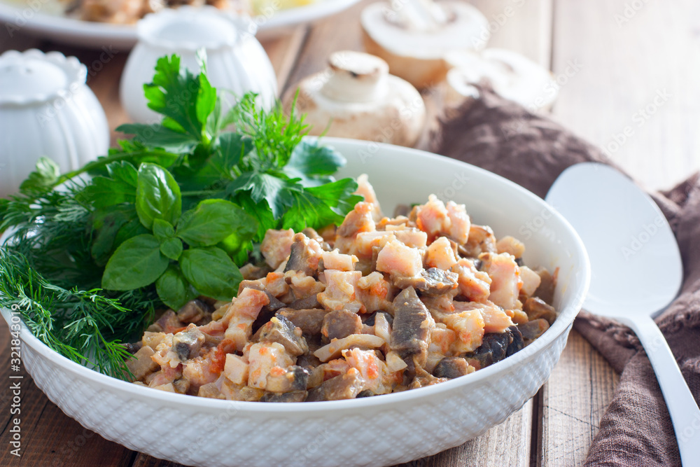 Salad with smoked chicken and fried champignons in a white plate on a wooden table with fresh herbs, selective focus Salad with smoked chicken and fried champignons in a white plate on a wooden table with fresh herbs, selective focus
