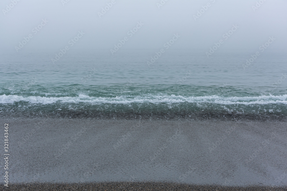 Sandy beach with the calm sea on a foggy day Sandy beach with the calm sea on a foggy day
