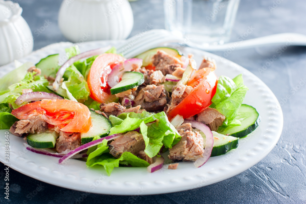 Salad with tuna and fresh tomatoes, cucumber and onions, on a white plate, selective focus Salad with tuna and fresh tomatoes, cucumber and onions, on a white plate, selective focus
