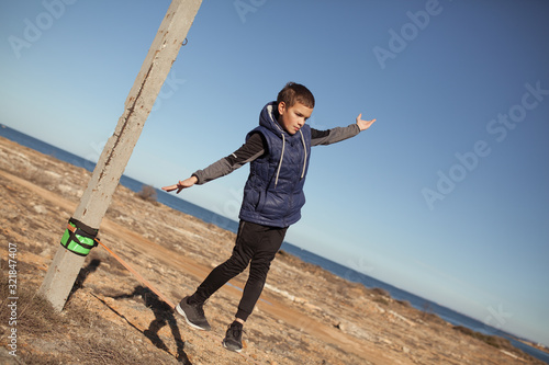 Young caucasian slackliner man doing slackline near the sea on day. photo