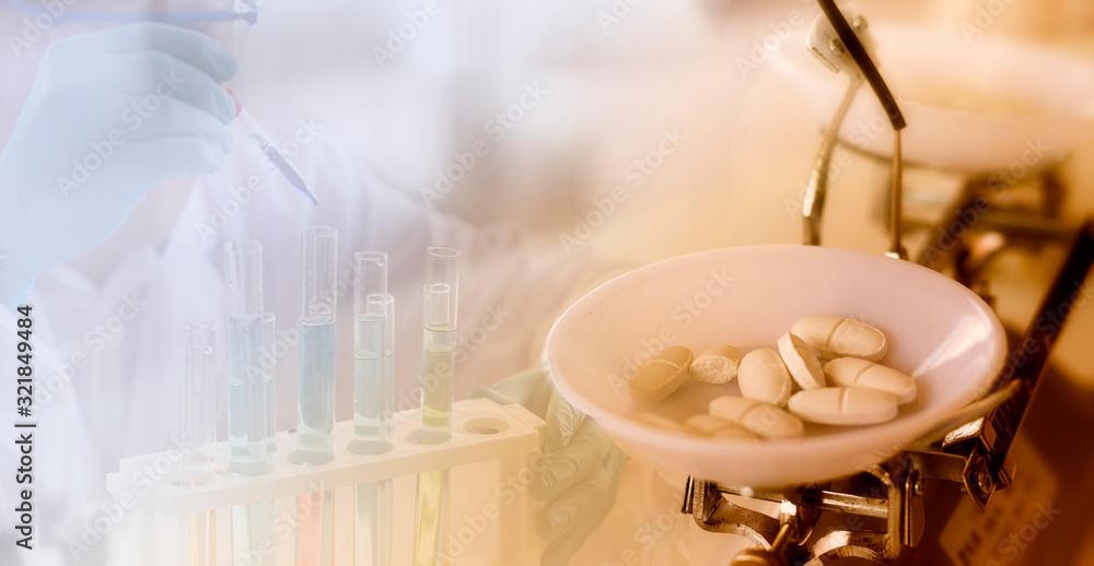 Fototapeta premium Medicine concept: White pills on mechanical balance with a blurred background of a scientist is researching in the laboratory.