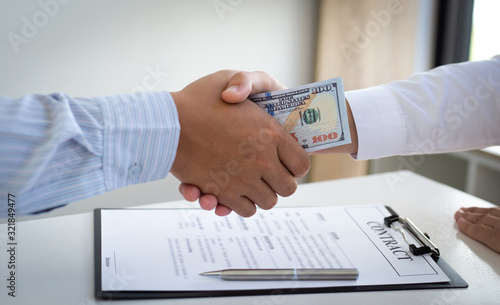  Businessmen make dollar payments while signing an investment agreement to be a partner in an illegal and successful manner, Bribery and corruption concept..