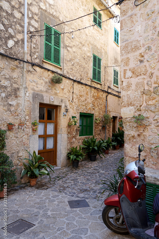 Picturescue street of Valldemossa with red scooter. Majorca, Spain