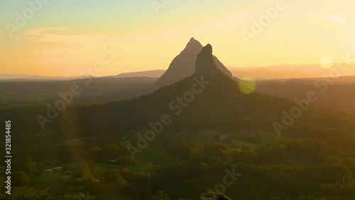 Left to right panning motion view of the Glasshouse mountains of Mount Beerwah and Mount Coonowrin at sunset from the top of Mount Ngungun with sun flare on the sunshine coast,Queensland,Australia photo