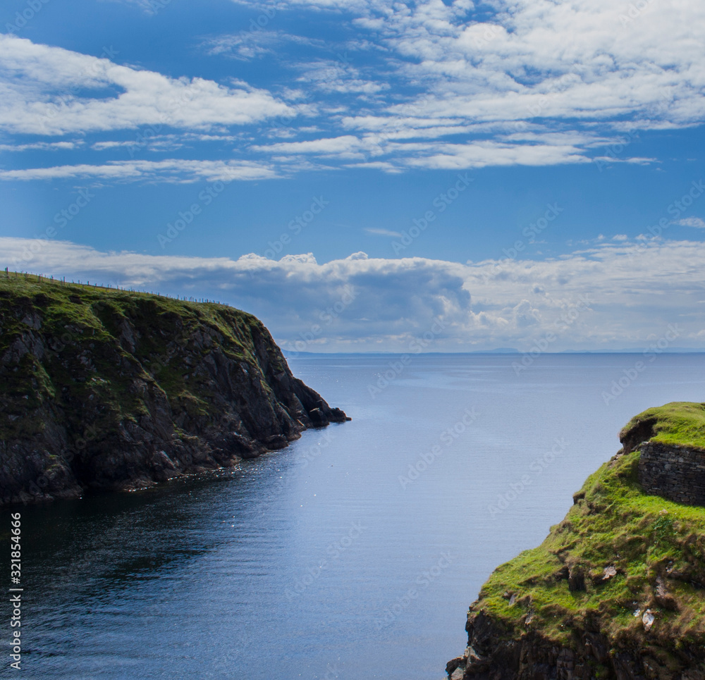 Rugged Donegal cliffs with bright blue sea and sky.
