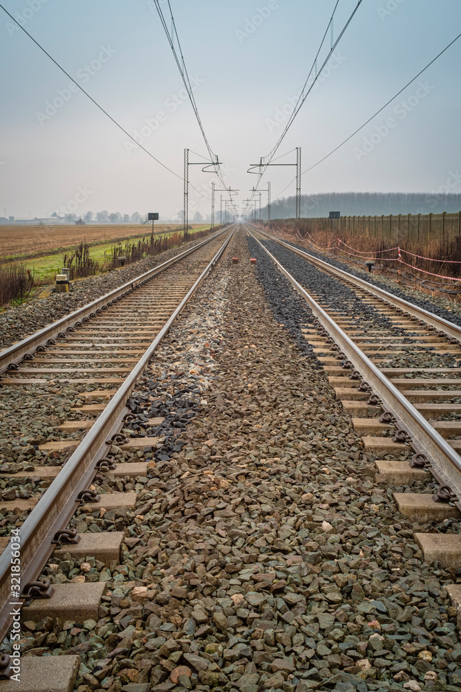 Perspective view of a railways toward the horizon, in the countryside region of Lomellina (between Lombardy and Piedmont, Northern Italy), famous for its rice cultivations.