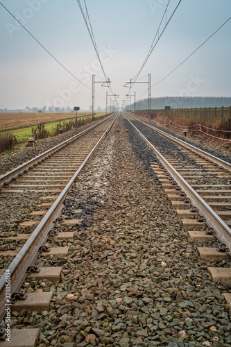 Perspective view of a railways toward the horizon, in the countryside region of Lomellina (between Lombardy and Piedmont, Northern Italy), famous for its rice cultivations.