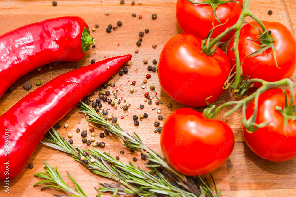 Close-up photo of red hot peppers, tomatoes with pepper peas and rosemary at the cutting board. Vegan food concept. Agriculture and harvesting. Top view Close-up photo of red hot peppers, tomatoes with pepper peas and rosemary at the cutting board. Vegan food concept. Agriculture and harvesting. Top view