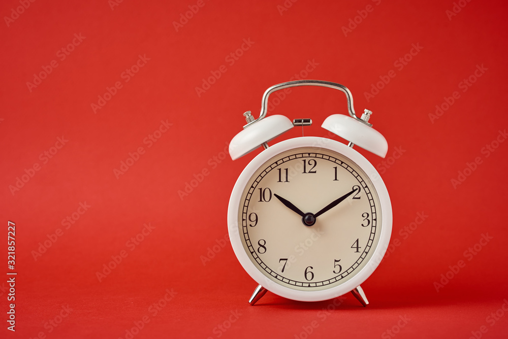 White retro alarm clock on the red background with copy space. Time concept White retro alarm clock on the red background with copy space. Time concept